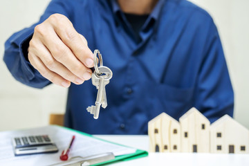 Real estate agent giving keys to property owner, sale purchase property deal concept