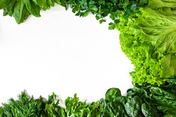 Obraz premium Green vegetables. Green fruits and vegetables on a white background. Apples, parsley, spinach, arugula and lettuce on a white background. Top view. Spinach and vegetable smoothies with copy space