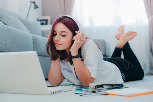 young girl teenage schoolgirl sits floor living room sofa student studying home working with her laptop doing homework - Powered by Adobe