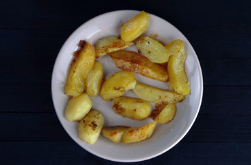  rustic potato lies on a plate on a black background