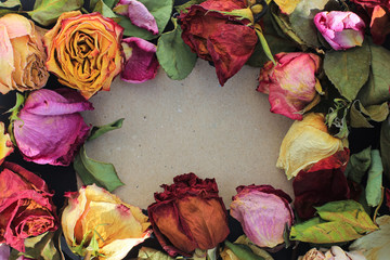Frame of laid out dry buds of roses, petals, leaves on craft and black paper background with copy...