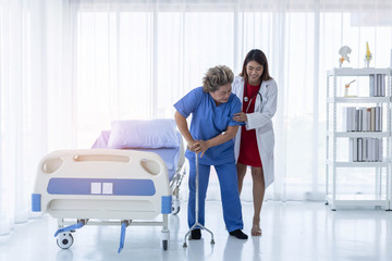 Obraz premium Young attractive Asian doctor is helping an old patient walking, hospital and healthcare concept.
