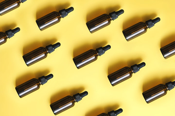 Flat lay pattern of natural cosmetics from small glass oil bottles. Jars with organic essential on yellow background