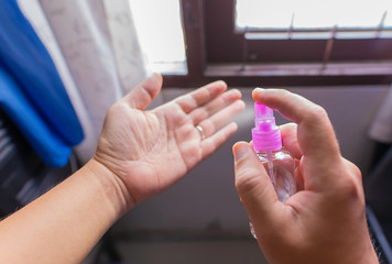 High angle view on person applying spray disinfection alcohol on hand disinfecting hands against virus bacteria health prevention in day at home or work.