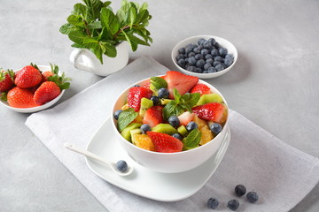 Bowl of healthy fresh colorful fruit salad on wooden background. Top view.Fruit salad with strawberry, blueberry, sweet cherry, kiwi.Vegetarian food concept. Rustic wooden background
