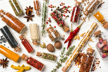 Different spices, dry kitchen herbs and seeds in glass vials for tasty meals