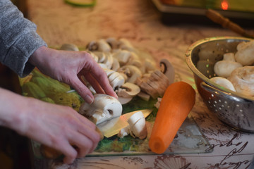 Woman cuts mushrooms in the kitchen