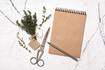 Fresh rosemary spice and scissors with mock-up of craft paper notebook