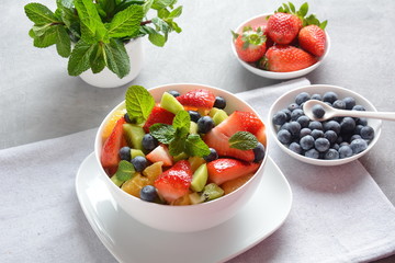 Bowl of healthy fresh colorful fruit salad on wooden background. Top view.Fruit salad with strawberry, blueberry, sweet cherry, kiwi.Vegetarian food concept. Rustic wooden background