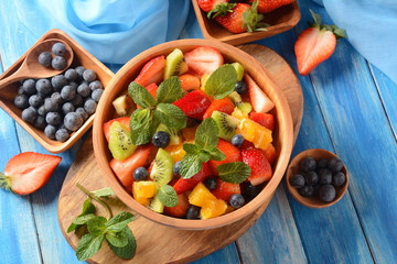Bowl of healthy fresh colorful fruit salad on wooden background. Top view.Fruit salad with strawberry, blueberry, sweet cherry, kiwi.Vegetarian food concept. Rustic wooden background