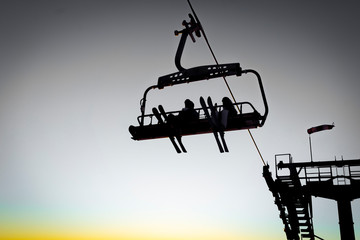 Silhouettes of skiers on chair lifts in the evening