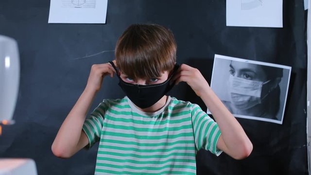 A schoolboy puts on a face mask. Manufactured house masks, self-isolation. The adaptability of life to the conditions of viral infection.