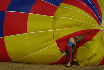 A woman is busy inflating a colorful hot air balloon