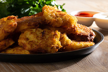 Fried potato pancakes with sauces and fresh herbs closeup. Belorussian or Ukrainian national cuisine