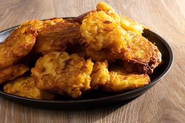 Potato pancakes in a black metal plate on a brown wooden table. Belorussian national cuisine