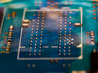 A macro shot of a blue circuit board covered with water.