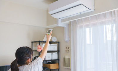 Woman control air conditioner power on in Japanese living room