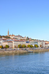 Fototapeta na wymiar Beautiful cityscape of Budapest, Hungary. Matthias Church, Fishermans Bastion and the historical center in the far background. Waters of the Danube river in the foreground. Vertical photo
