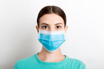 Portrait of young woman wearing medical mask at white background. Protect your health. Coronavirus concept