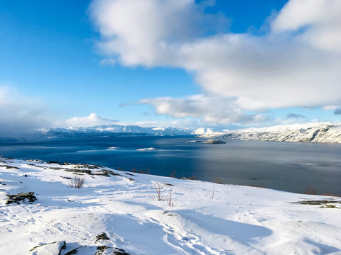 Beautiful Fjord view with clouds and blue water from a snowy mountain in Alta Norway - Landscape Photography