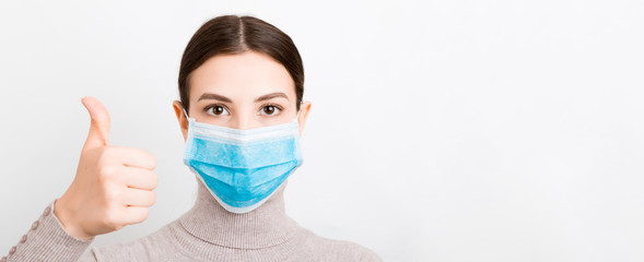 Portrait of young woman wearing medical mask at white background. Person is happy because she is finally healthy. Protect your health. Coronavirus concept