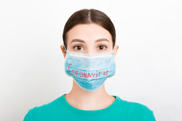 Portrait of a sad woman in medical mask with coronavirus text at white background. Coronavirus concept. Respiratory protection