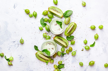 Smoothies from gooseberry with kiwi and yogurt, chia seeds, gray kitchen table background, flat lay, top view