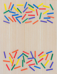 Multi-colored sticks on a wooden background. View from above. Background for text. Copy space