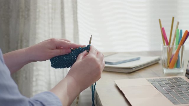 Woman Watches Knitting Tutorial On Her Laptop In Her Home Office, Follows Along