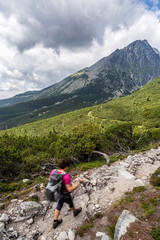 Fototapeta na wymiar Young woman on a mountain terrain trail. Hiking in High Tatras National Park, Slovakia.