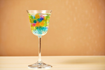 A wine glass filled with many colorful jelly balls and beverage. Fizzy exotic drink. Copy space for your text. Bars and parties