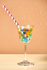 Exotic cocktail with fizzy drink and colourful jelly balls and long straw inside. Party and bar equipment.