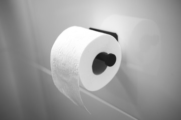 Roll of one white toilet paper on wall