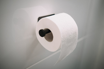 Roll of one white toilet paper on wall