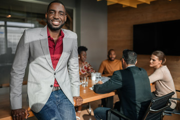 Casual portrait of professional black african business man, coworkers hold a meeting in background