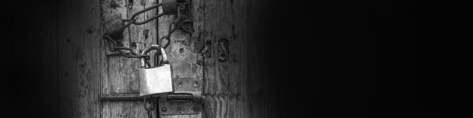 podlock with a chain on an old wooden door black and white