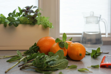 The process of making lemonade at home. Ingredients lemon, orange, mint are on the gray kitchen table. The concept of a healthy diet, lifestyle, and diet. Selective focus.