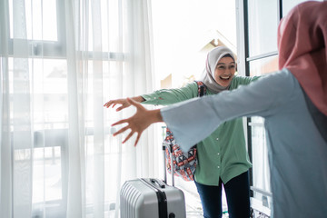 muslim hijab woman happily returns home opens the door and meets her sister