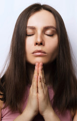 Beautiful young woman prays with closed eyes