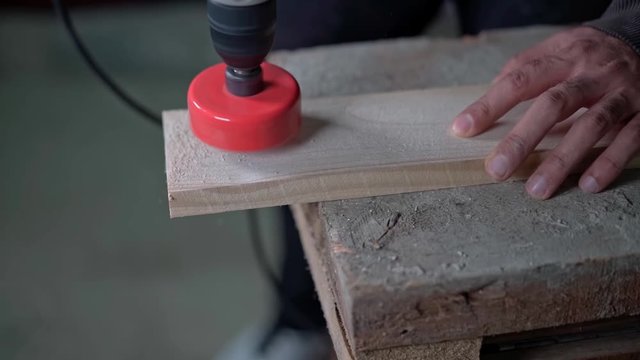 A drill with a circular nozzle cuts a circle in a wooden block