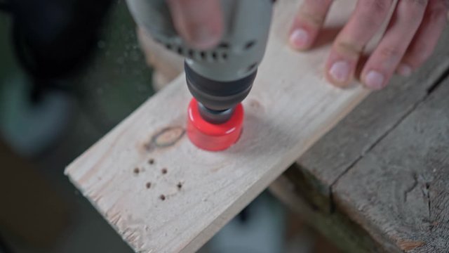 A drill with a circular nozzle cuts a circle in a wooden block