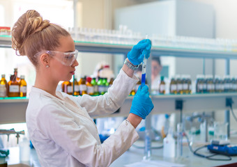 Beautiful young woman scientist in laboratory working. Young female scientist doing some research.