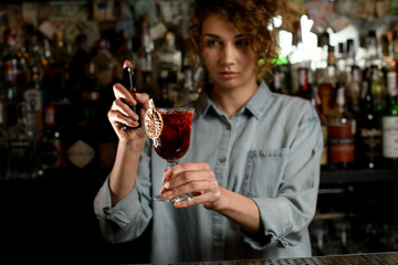 young woman bartender hold glass of drink in hand