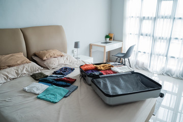 suitcase with lots of clothes on the bed, preparation before traveling