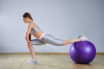 Fototapeta na wymiar Young fit woman exercising in a gym. Sports girl is training cross fitness with Pilates Balls.