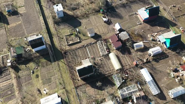Village street with houses, outbuildings and household plots in early spring. Shooting from a height.
