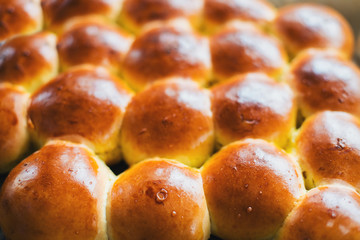 Ruddy buns on a baking sheet on a kitchen table. Bakery products