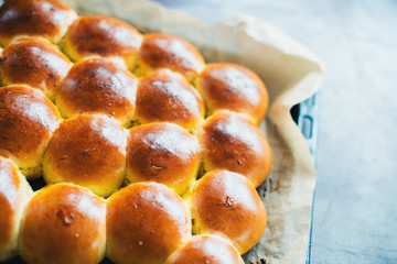 Ruddy buns on a baking sheet on a kitchen table. Bakery products