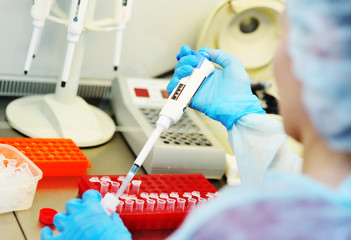 A young female scientist works in a sterile genetic or bacteriological laboratory with a dispenser...