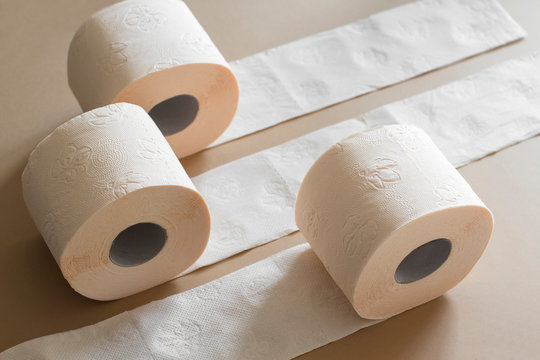 rolls of toilet paper peach beige color on beige background